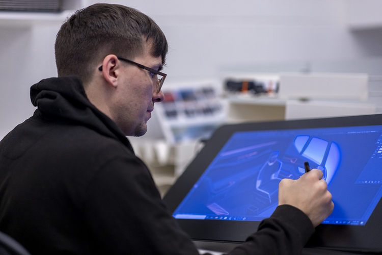 A Mack Trucks designer sketches a rendering of a truck cab’s interior on a large digital tablet using an electronic stylus.